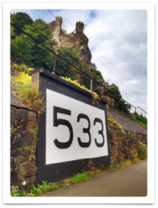 Rheinkilometer 533, fast zwei Meter hoch, Im Hintergrund eine Burg des Mittelrheintals.